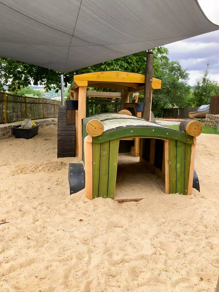 Spielplatz aus Holz mit einem großem Holzauto